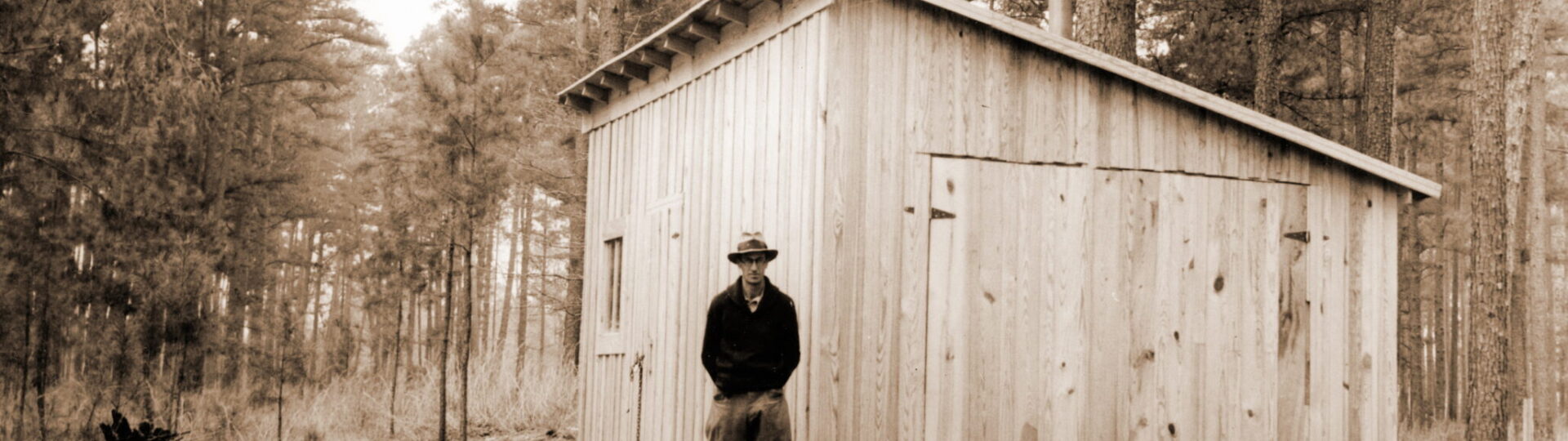 First building on the new Crossett Experimental Forest and Research Center, 1934. Building was used as tool shed and office until permanent office and other buildings were constructed at the headquarters area 1/4 mile south. Building was started on December 22, 1933 and completed in a couple days. Building was located at what now is the picnic ground area. Russ Reynolds by building.